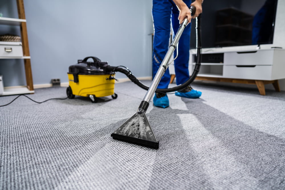 Person saugt einen Teppich mit professionellem Sauger